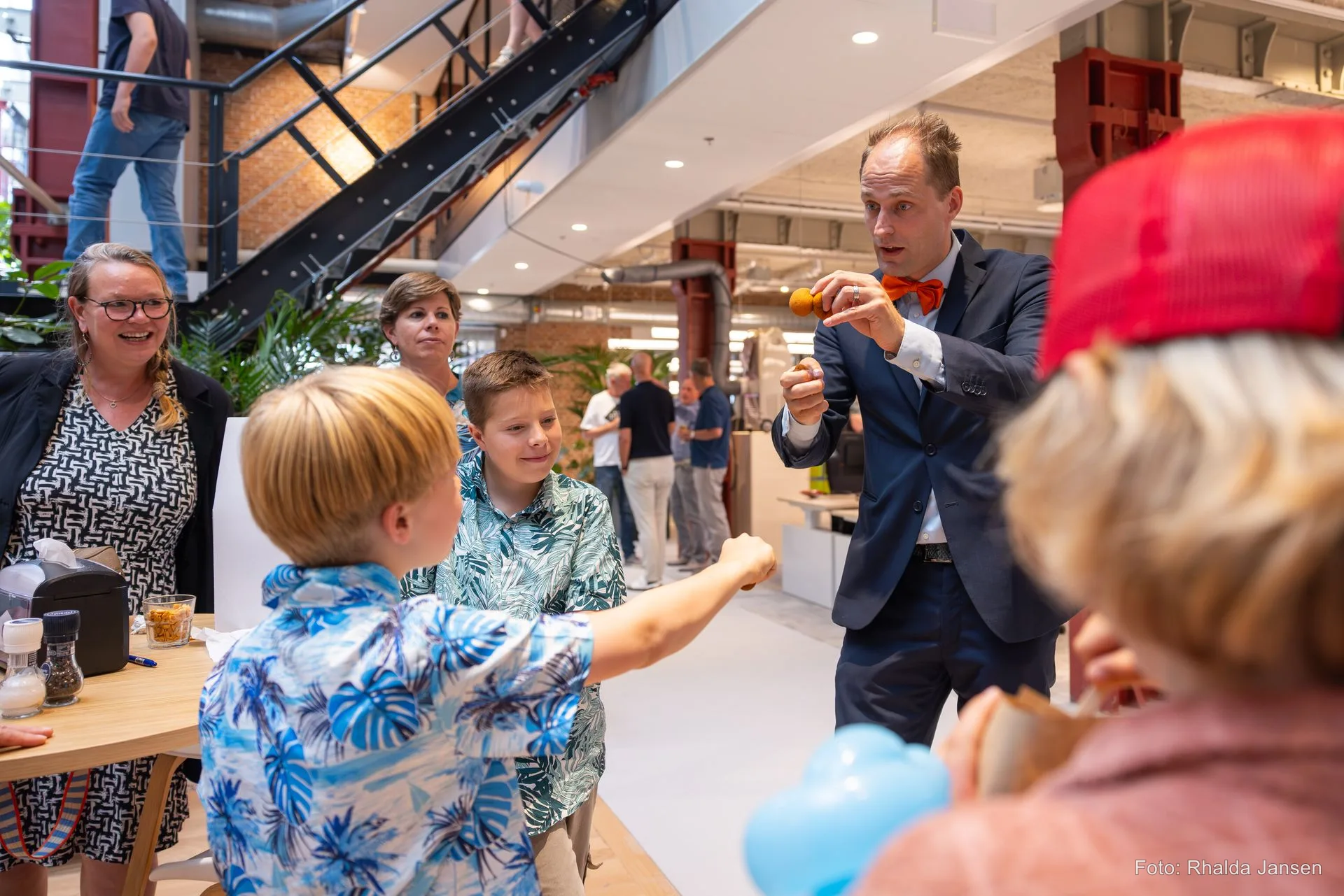 Goochelaar Teun Rookus laat een prop zien aan kinderen en ouders tijdens een bedrijfsevent — iedereen kijkt geboeid toe