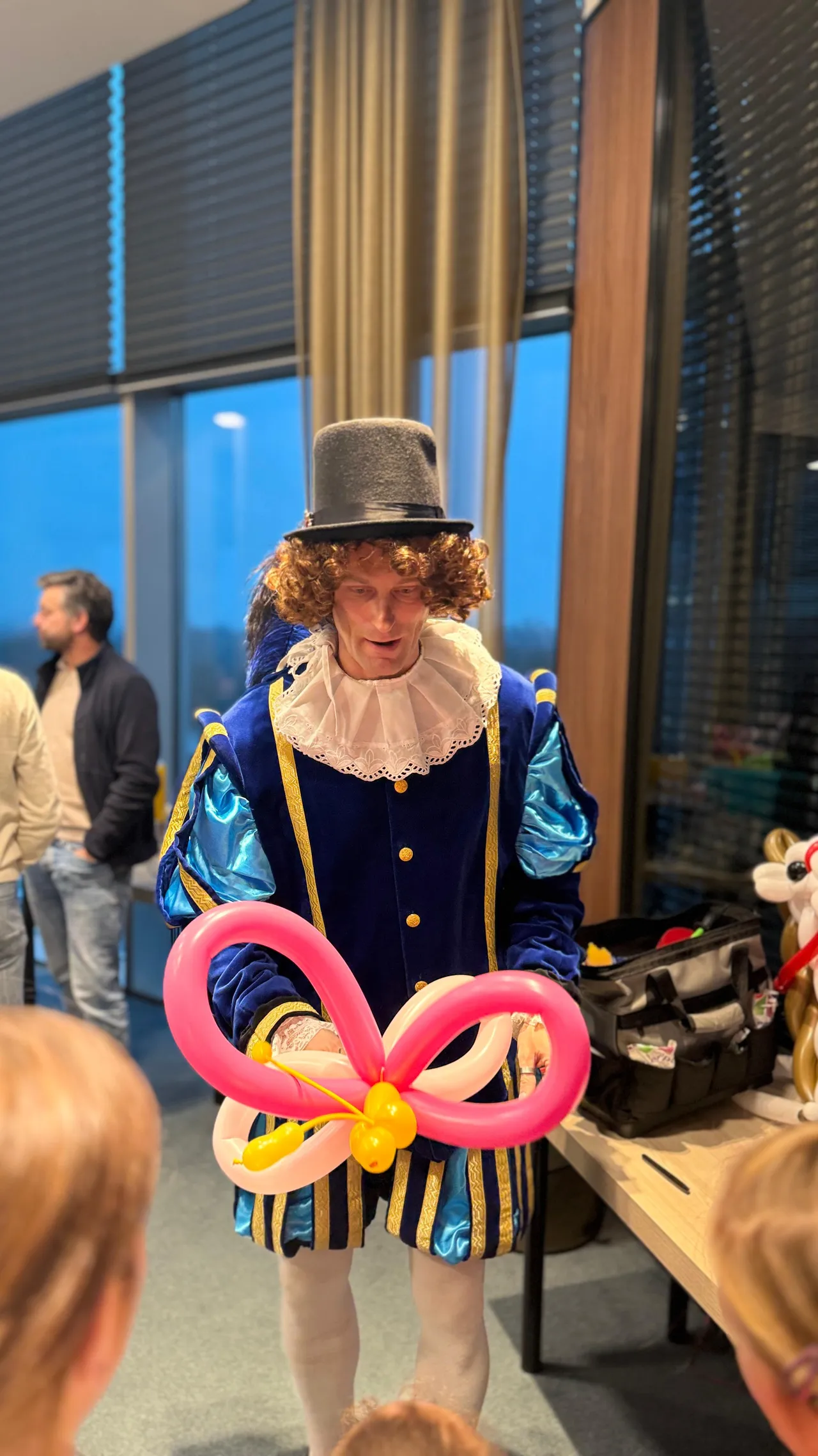 Hocus Pocus Piet vouwt een roze vlinder-ballon voor een kind